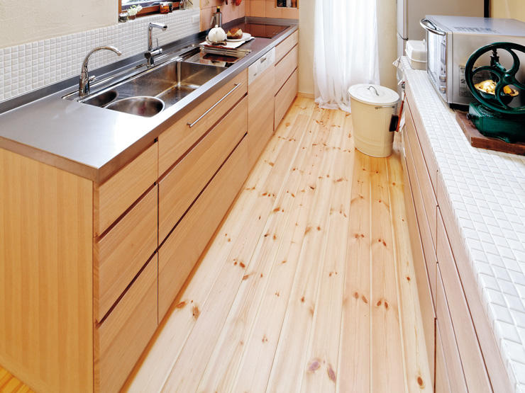 パインフローリングを木目調のキッチンと白いモザイクタイルと色調を合わせて明るい空間に。